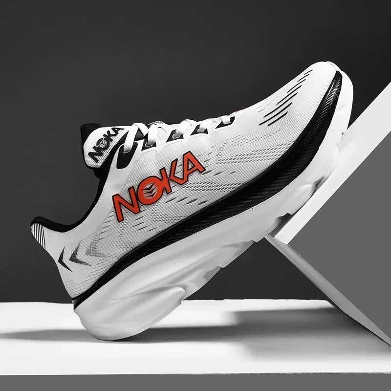 White running shoe with black accents and red 'Noka' branding on a gray background
