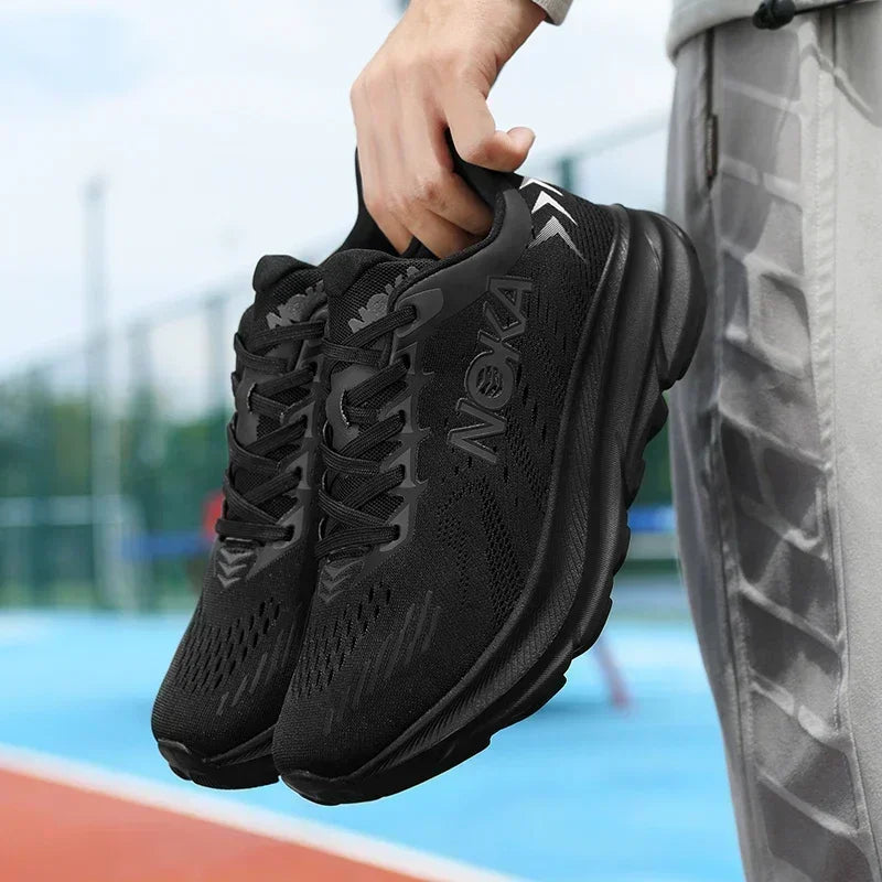 Person holding black athletic shoes with a blurred sports field background