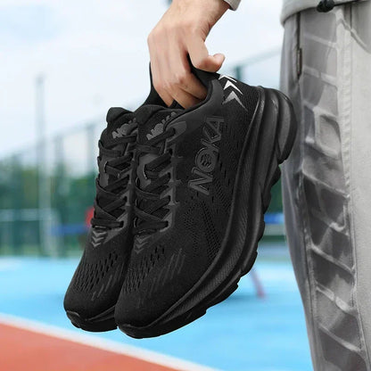 Person holding black athletic shoes with a blurred sports field background